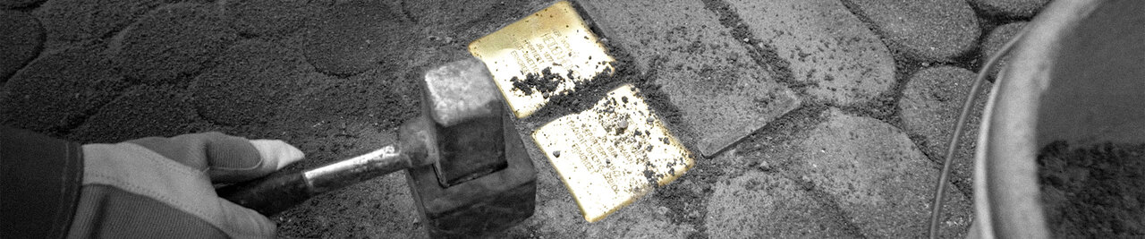 Detailaufnahme von zwei Stolperseinen bei der Verlegung, links eine Hand die einen Hammer hält, rechts ein Eimer, alles schwarzweiß bis auf die goldenen Erinnerungssteine