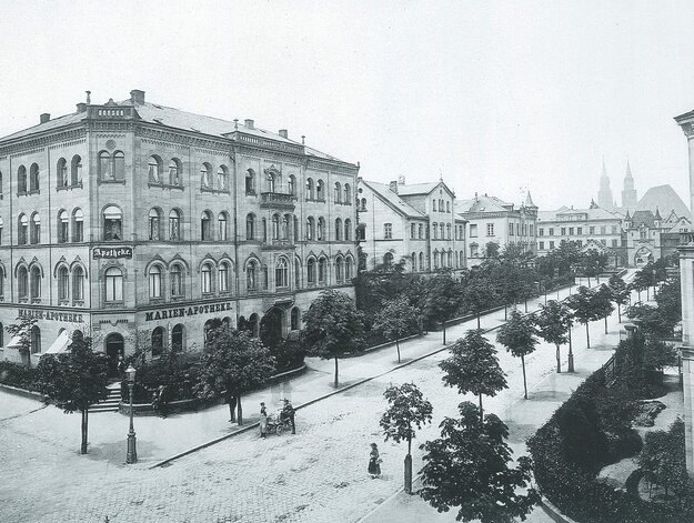 Historische Aufnahme der Marienvorstadt, links ein großes Gebäude mit der Aufschrift 'Marienapotheke', rechts eine von Bäumen flankierte Straße