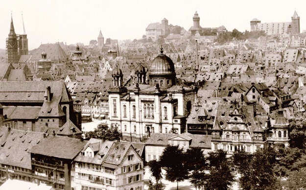 Historische Aufnahme der Nürnberger Altstadt, im Zentrum eine Synagoge umgeben von Hausdächern, im Hintergrund die Kaiserburg