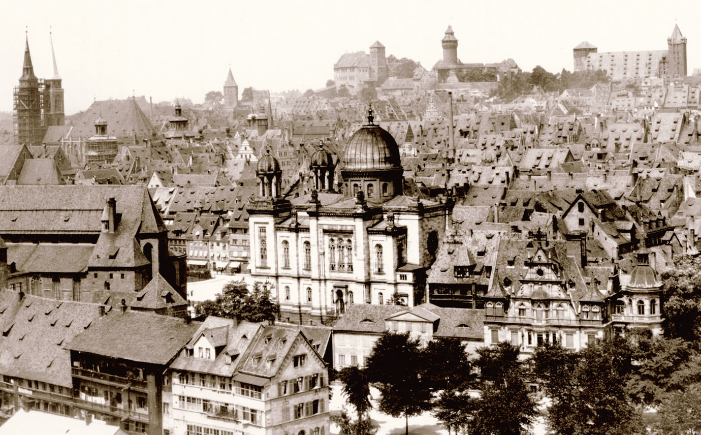 Historische Aufnahme der Nürnberger Altstadt, im Zentrum eine Synagoge umgeben von Hausdächern, im Hintergrund die Kaiserburg