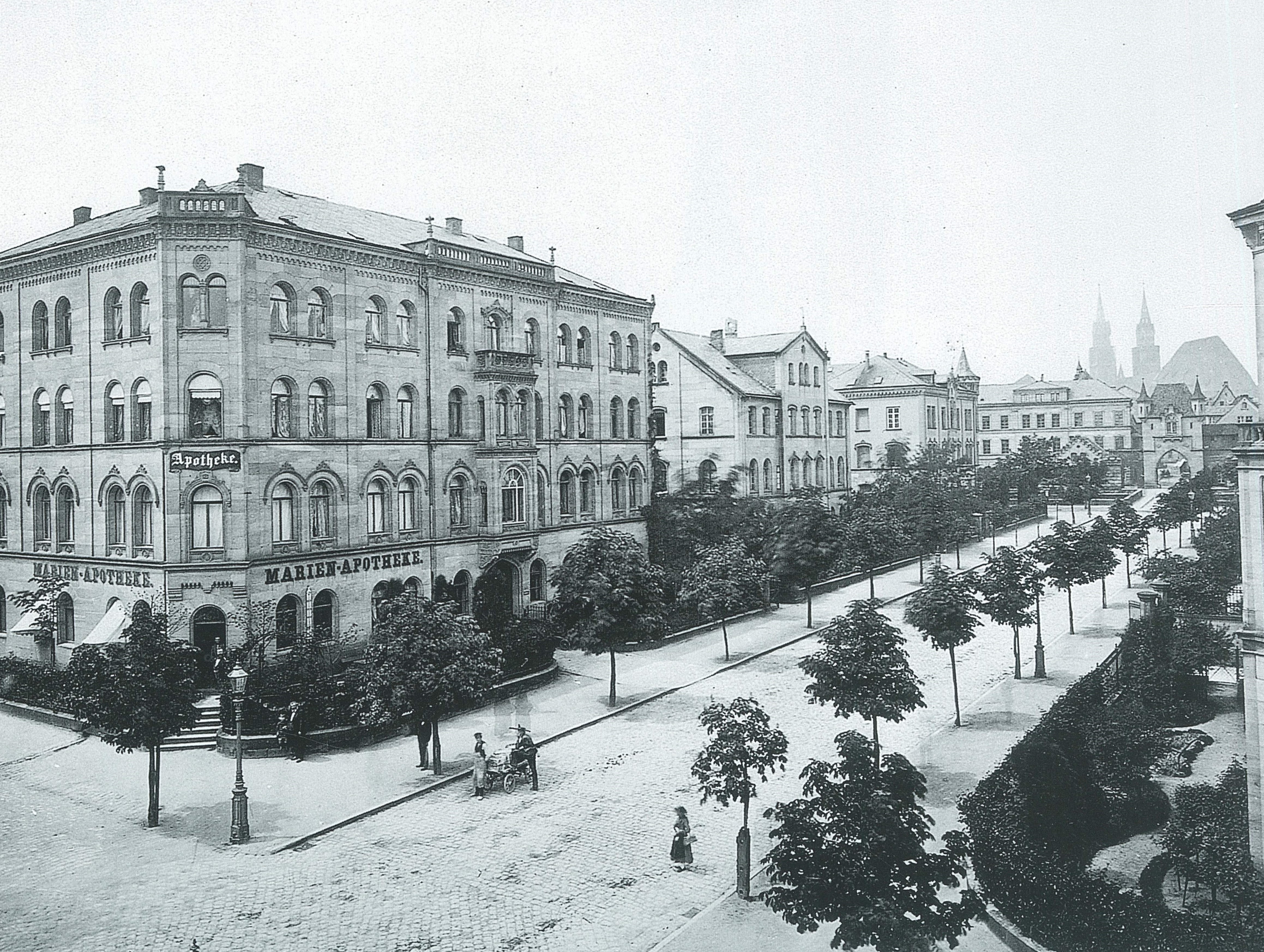 Historische Aufnahme der Marienvorstadt, links ein großes Gebäude mit der Aufschrift 'Marienapotheke', rechts eine von Bäumen flankierte Straße